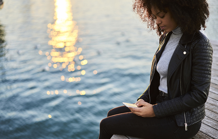 Junge affroamerikanische Frau welche auf dem Smartphone E-Banking benutzt